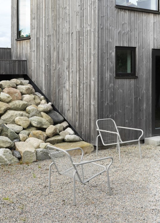 Zwei graue Vig Lounge Chairs von Normann Copenhagen im Außenbereich vor einem modernen Holzhaus.