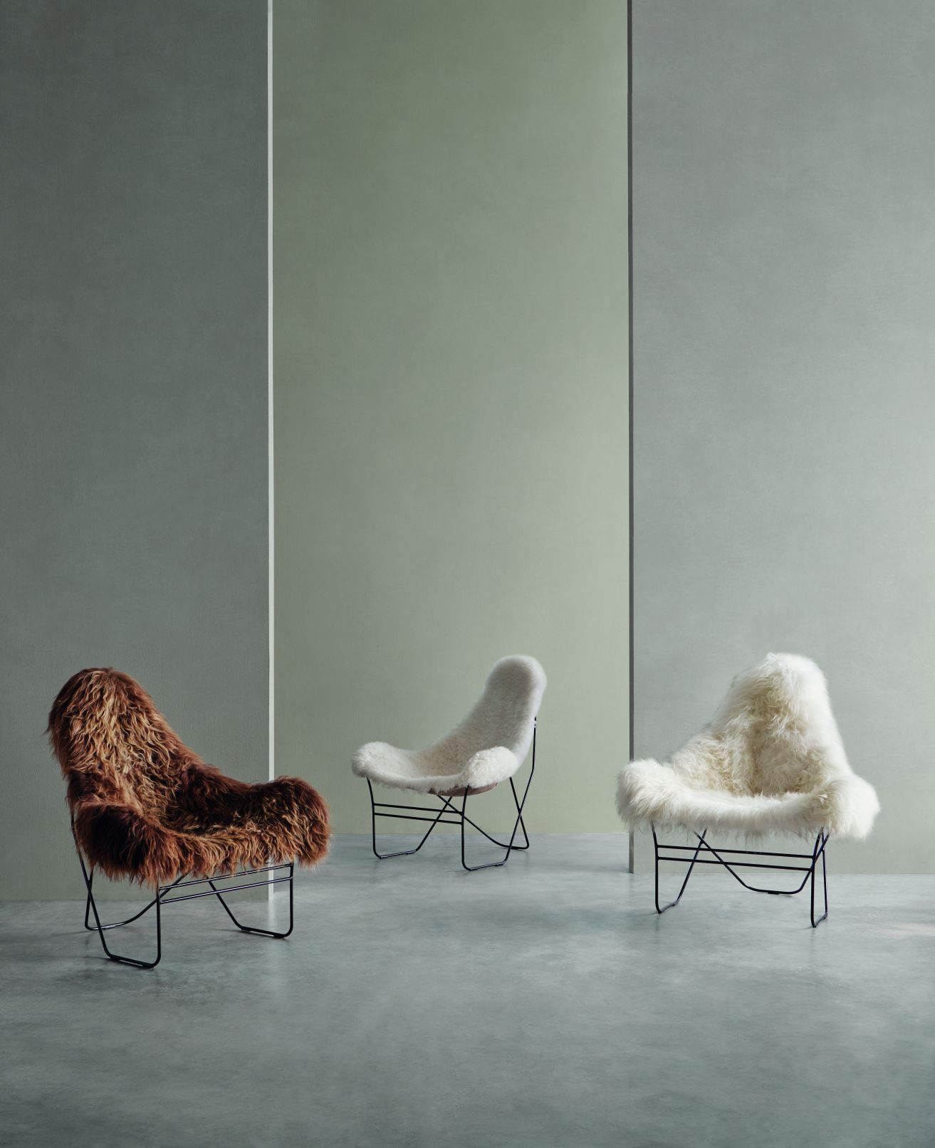 Drei luxuriöse Schaffell Sessel in Braun und Weiß mit modernem, schwarzem Metallgestell.
