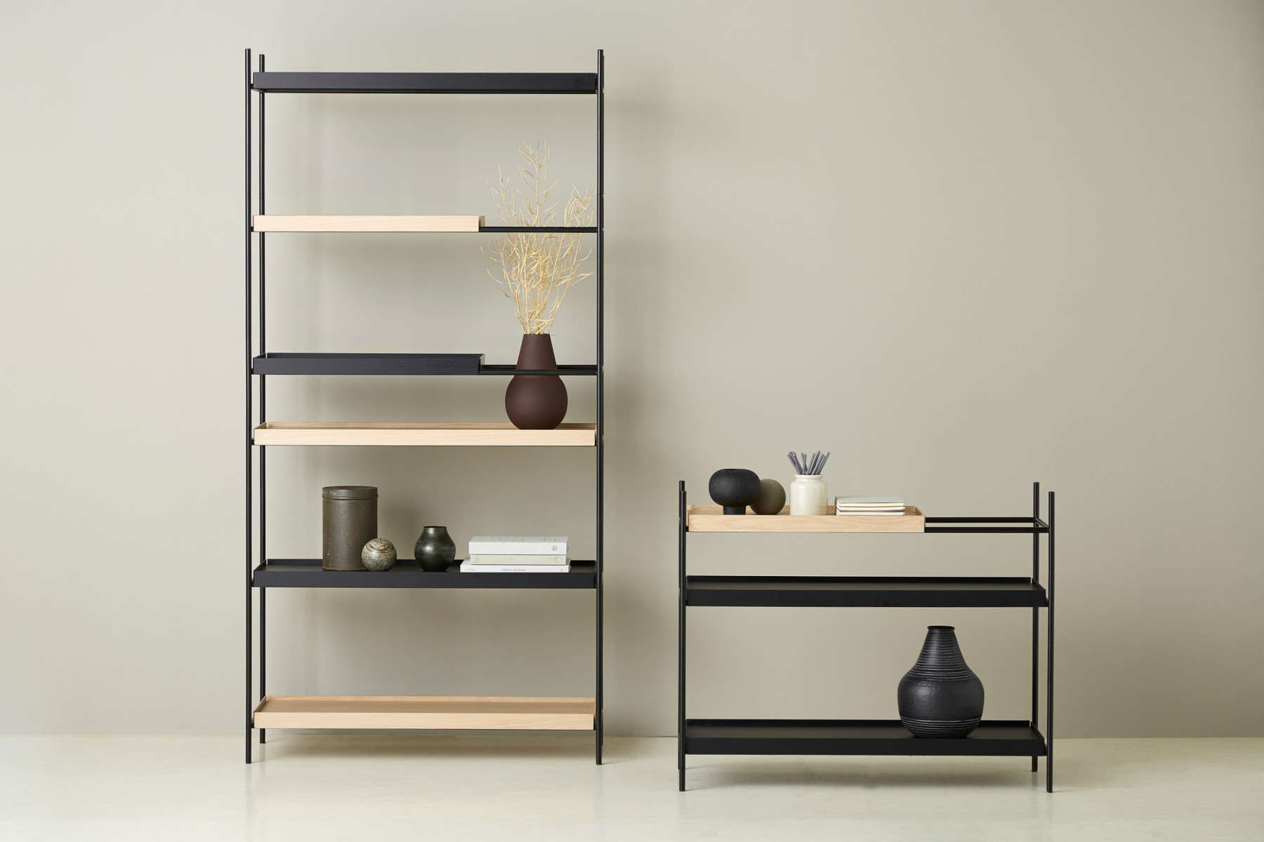 Modernes Regal-Set mit schwarzem Metallrahmen und Holzregalen, dekoriert mit Vasen und Büchern.
