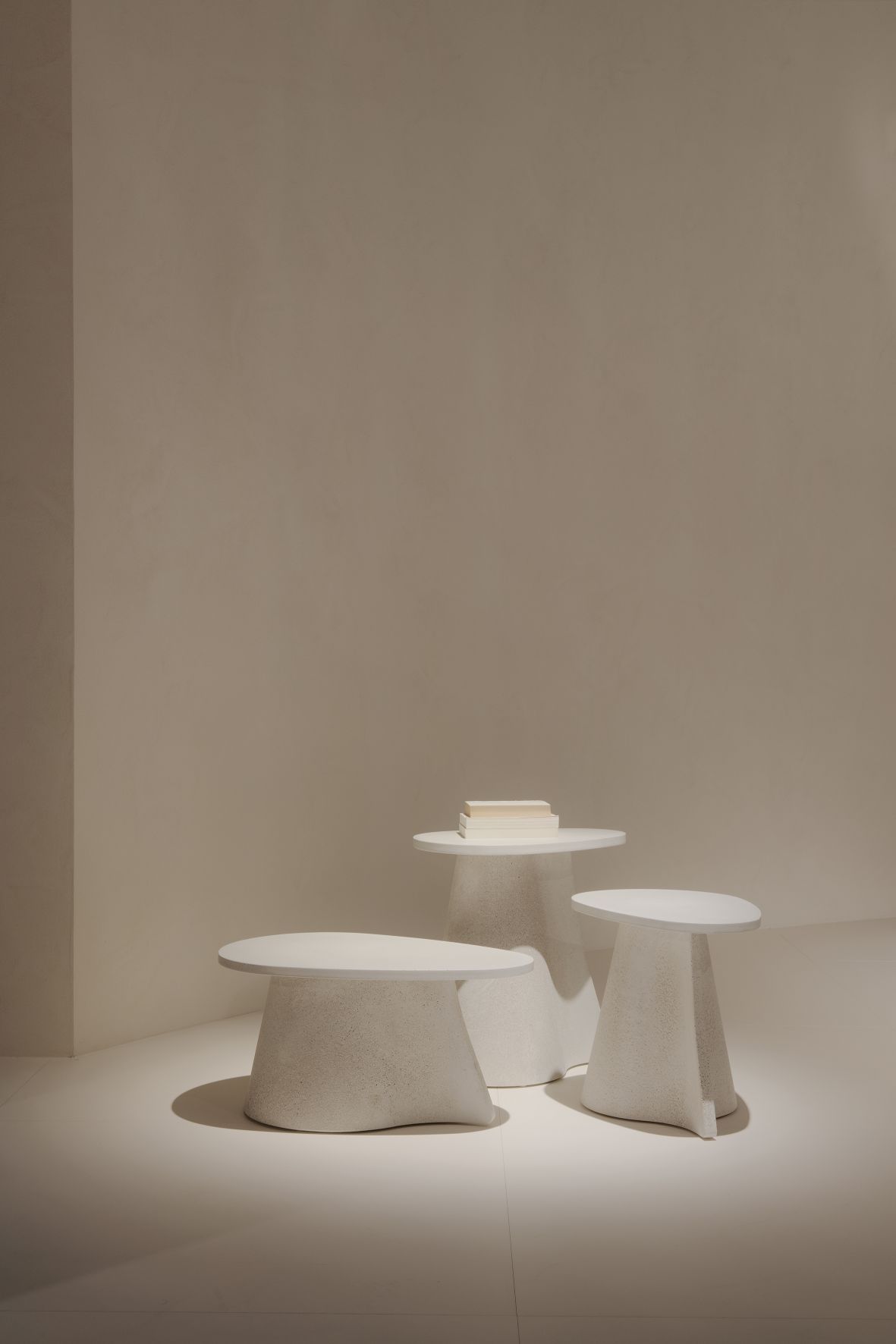 Nahaufnahme von drei weißen MDF Italia Fossil Beistelltischen in unterschiedlichen Höhen, modernes Wohnzimmer-Design.
