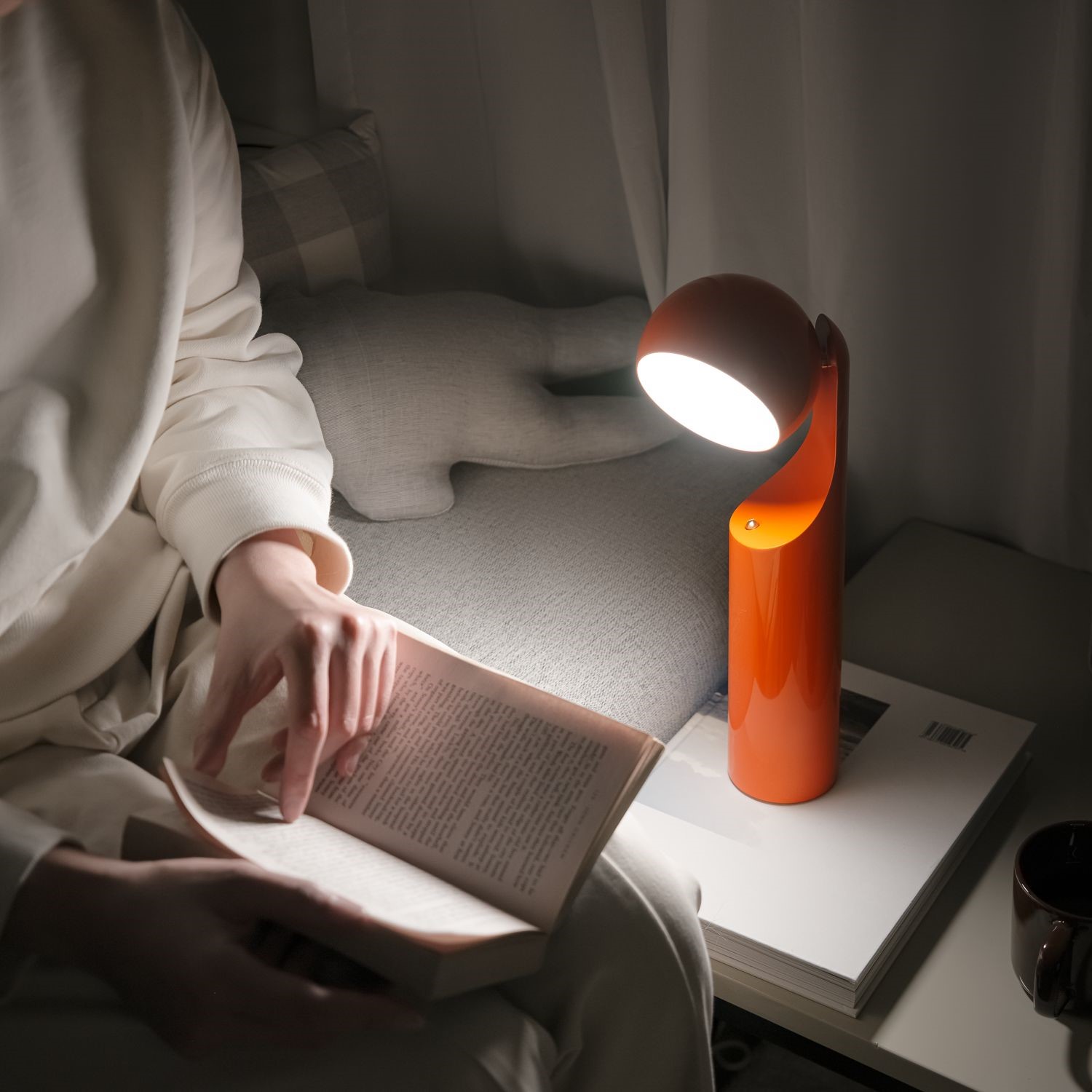 Frau liest mit der orangefarbenen Mono Portable Akkuleuchte von house of home.