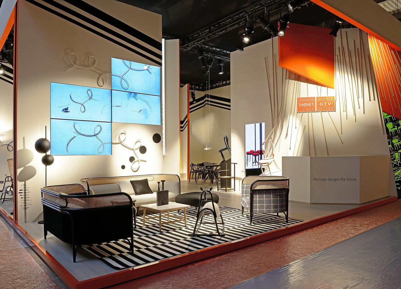 Ausstellungsstand mit Wiener GTV Design Möbeln, darunter Sessel, Sofa und Couchtisch auf einem schwarz-weiß gestreiften Teppich.