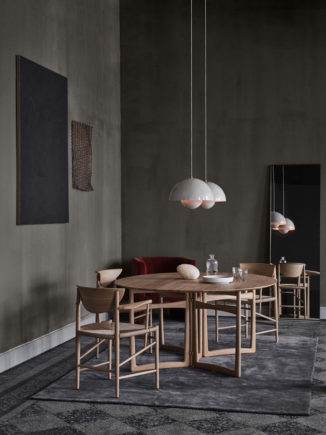 AndTradition Drop Leaf HM6 Esstisch aus Holz mit Stühlen und Pendelleuchten in stilvollem Ambiente.