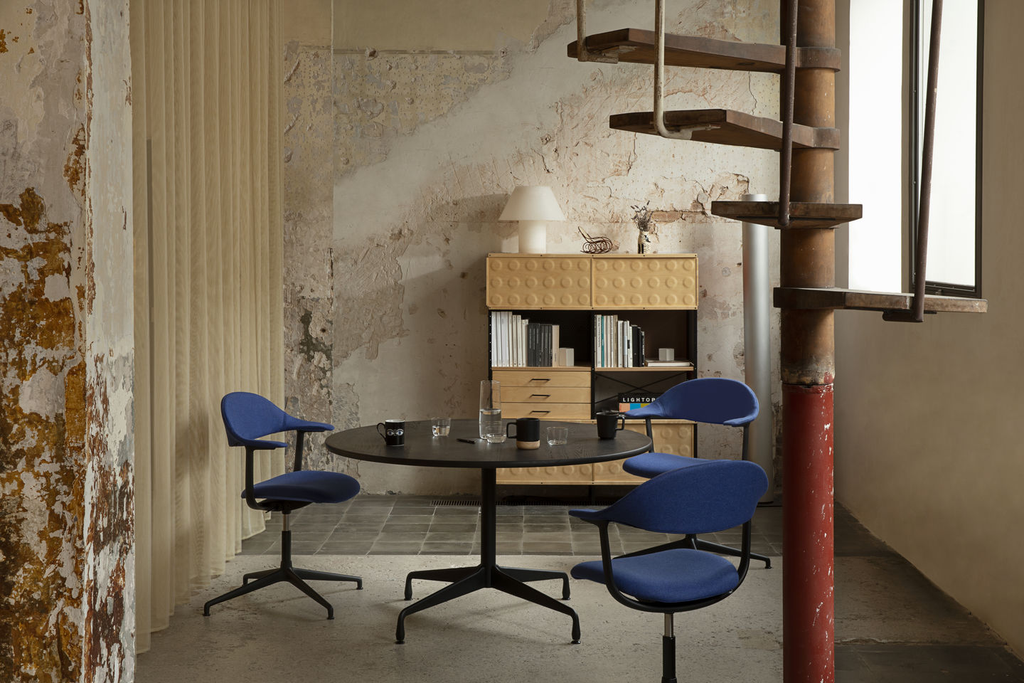 Mynt Bürodrehstühle von Vitra in blau um einen schwarzen Tisch in einem modernen Büro.