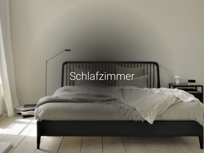 Modernes Schlafzimmer mit schwarzem Bettgestell, beiger Bettwäsche, Nachttisch und Stehlampe für stilvolles Wohnen.