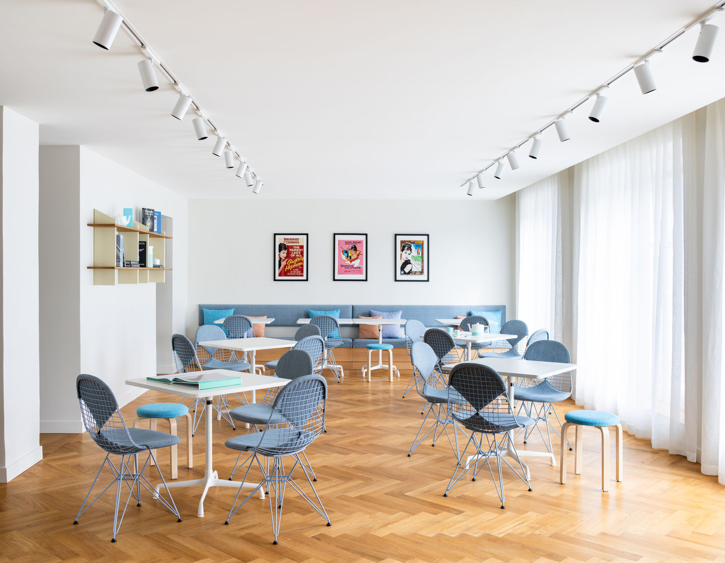 Heller Raum mit mehreren DKR Wire Chairs von Vitra mit Sitzpolster an weißen Tischen.