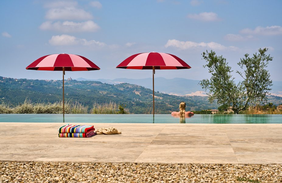 Weishäupl Pagodenschirm am Pool mit rot-weißem Stoff, Handtüchern und Blick auf die Landschaft.