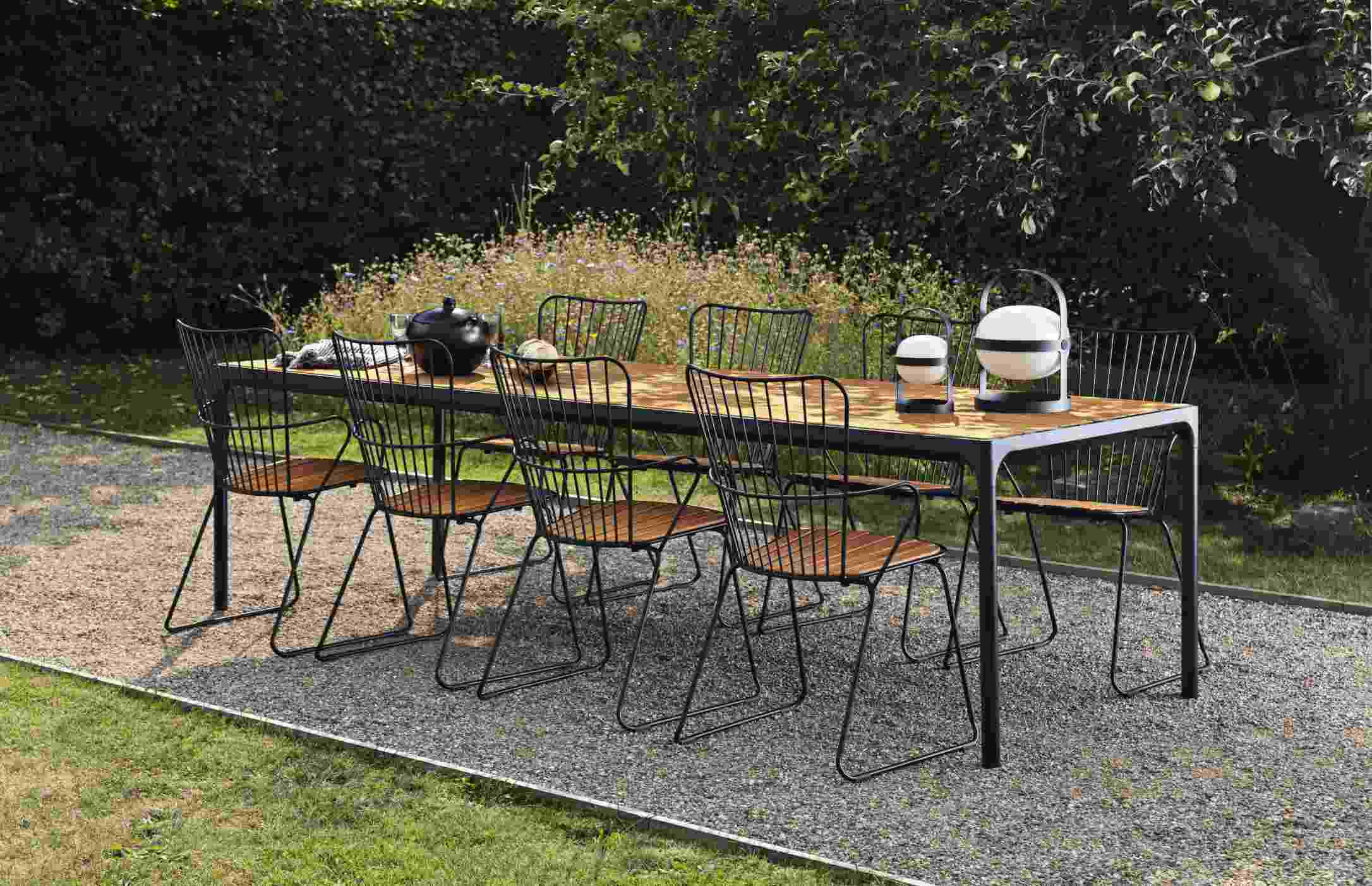 Houe Four Esstisch für den Garten mit sechs Stühlen und Gartendeko auf Kiesfläche.