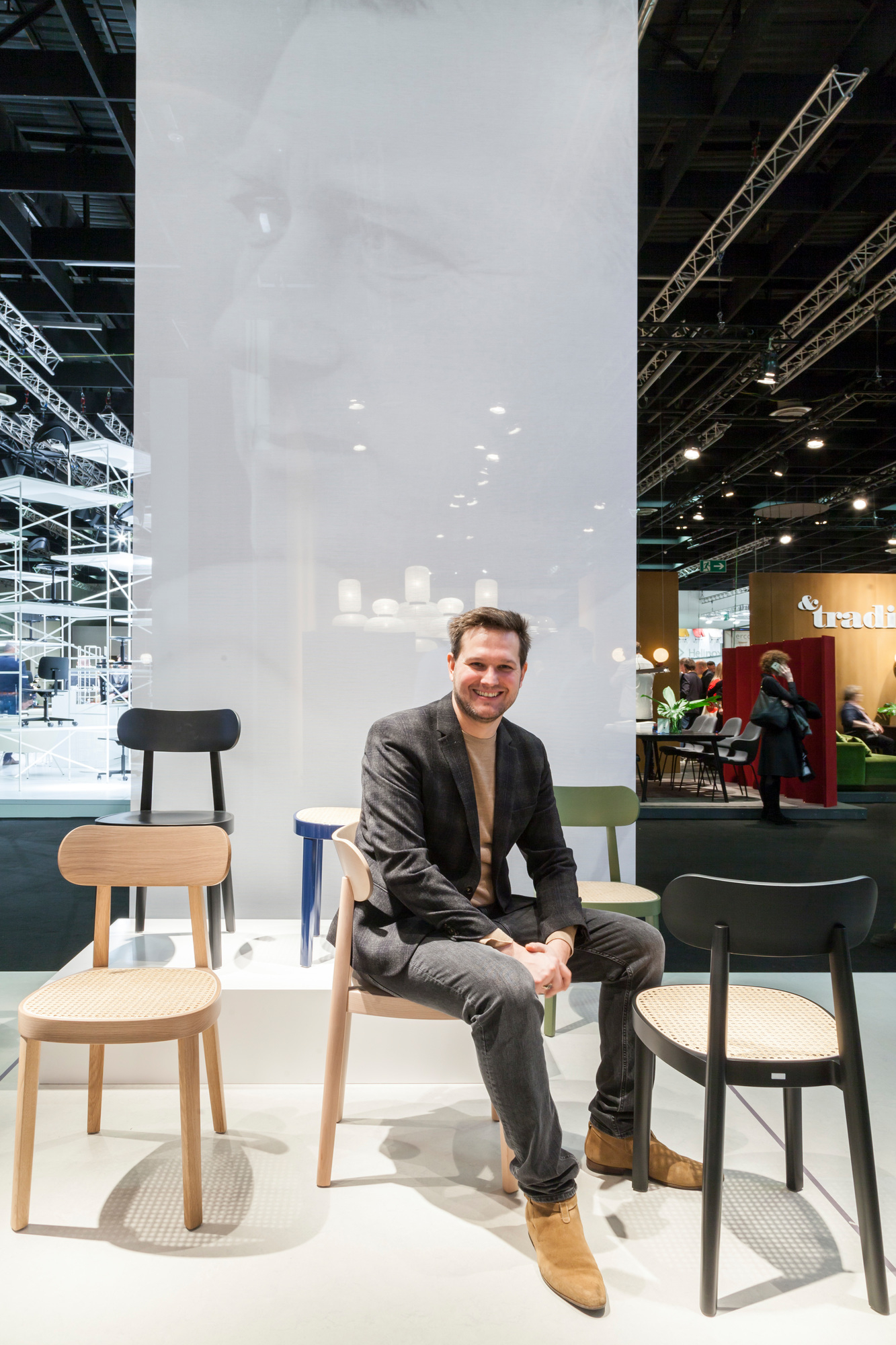 Mann sitzt auf einem Thonet Holzstuhl 118 M. Designklassiker mit Wiener Geflecht. Nussbaumholz.