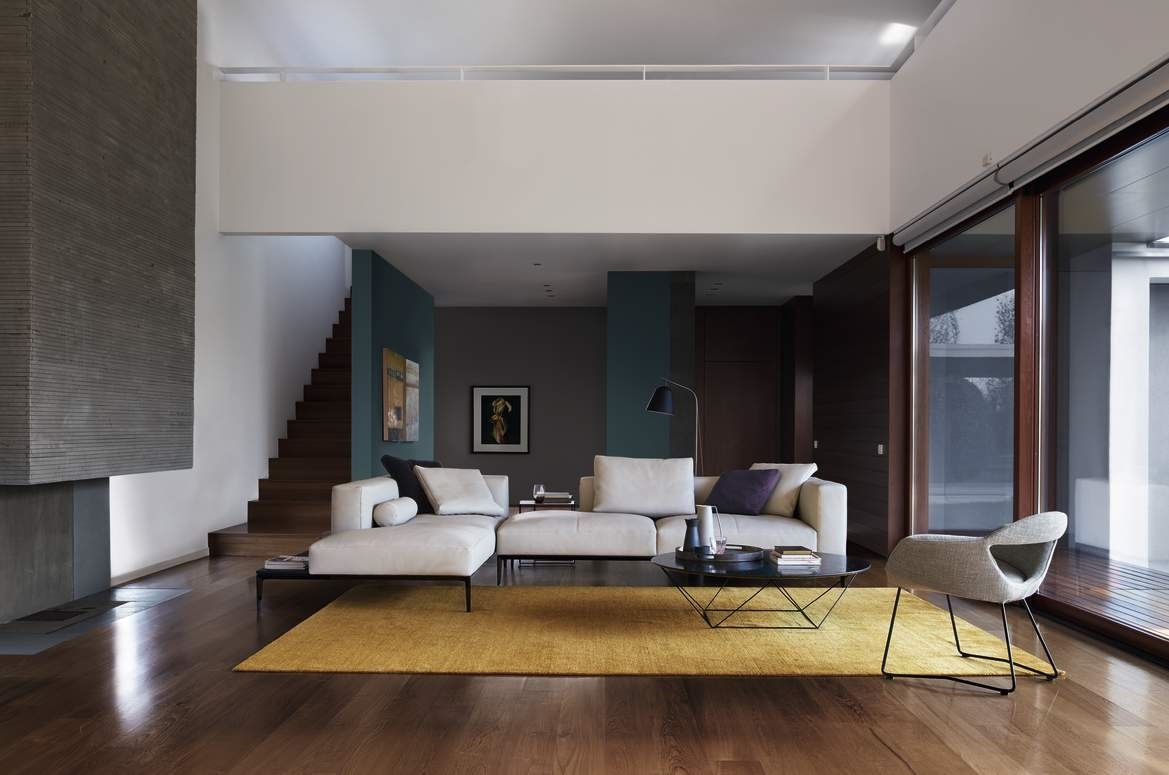 Heller Wohnraum mit Walter Knoll Sofa, Sessel, gelbem Teppich und schwarzem Oki Beistelltisch.