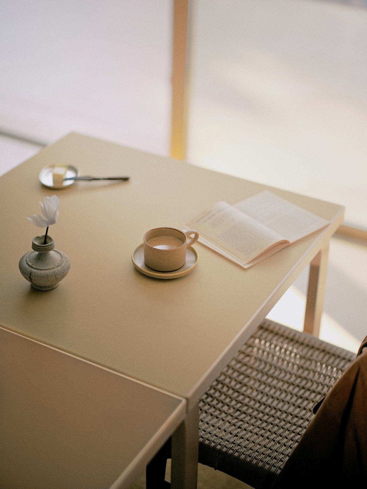 Detailaufnahme des Aalto Klapptischs von Artek mit Kaffeetasse, Buch und kleiner Vase.