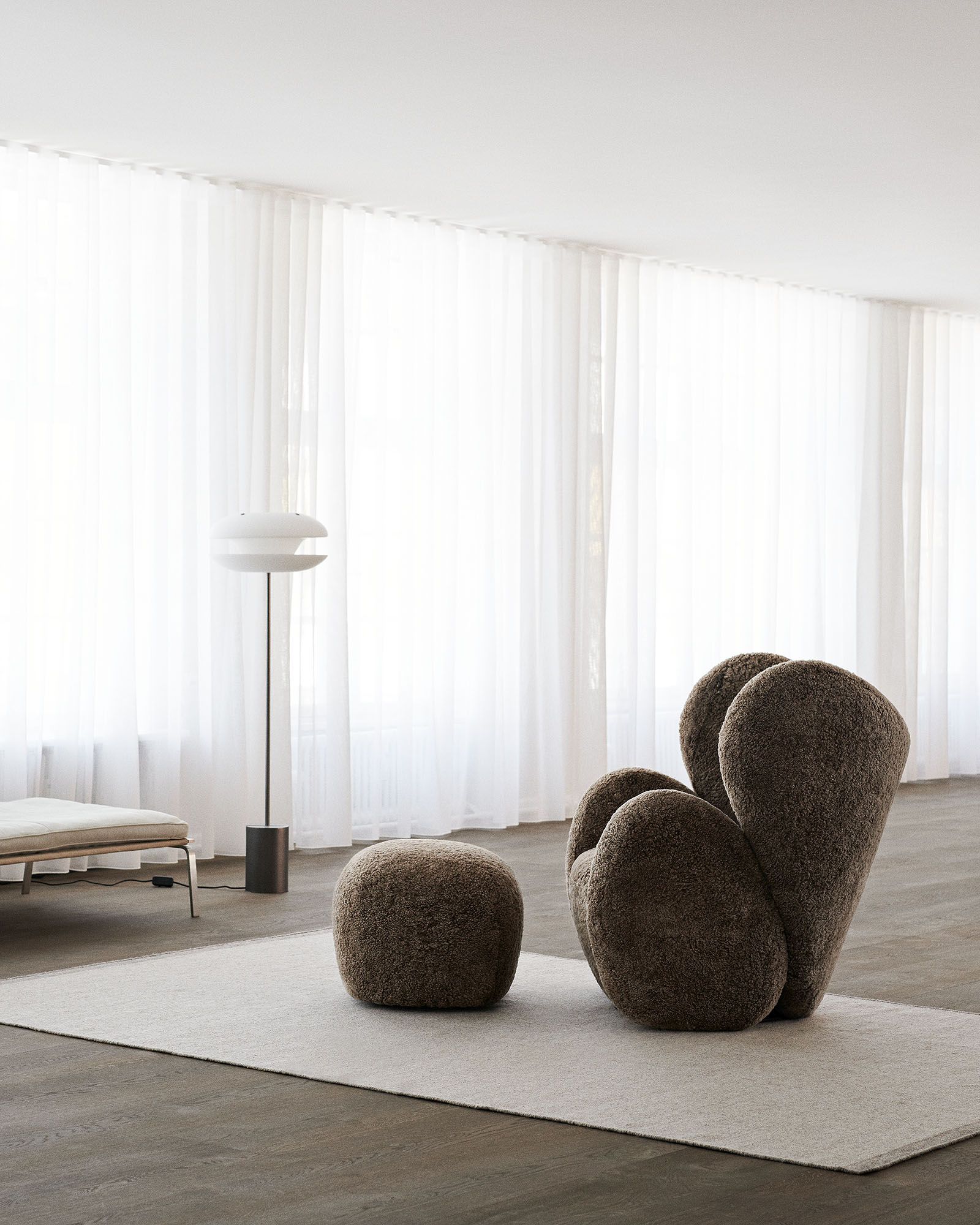 Big Big Lounge Chair Sessel von NORR11 mit passendem Hocker in modernem Wohnzimmer mit Teppich.