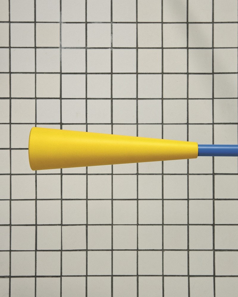 Nahaufnahme der Flos 265 Chromatica Wandleuchte mit gelbem Lampenschirm und blauem Arm vor Fliesenhintergrund.