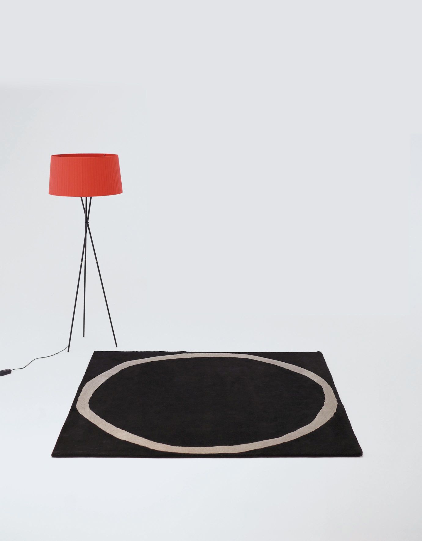 Rechteckiger Aros Teppich von Nanimarquina in Schwarz mit beigem Oval auf weißem Hintergrund.