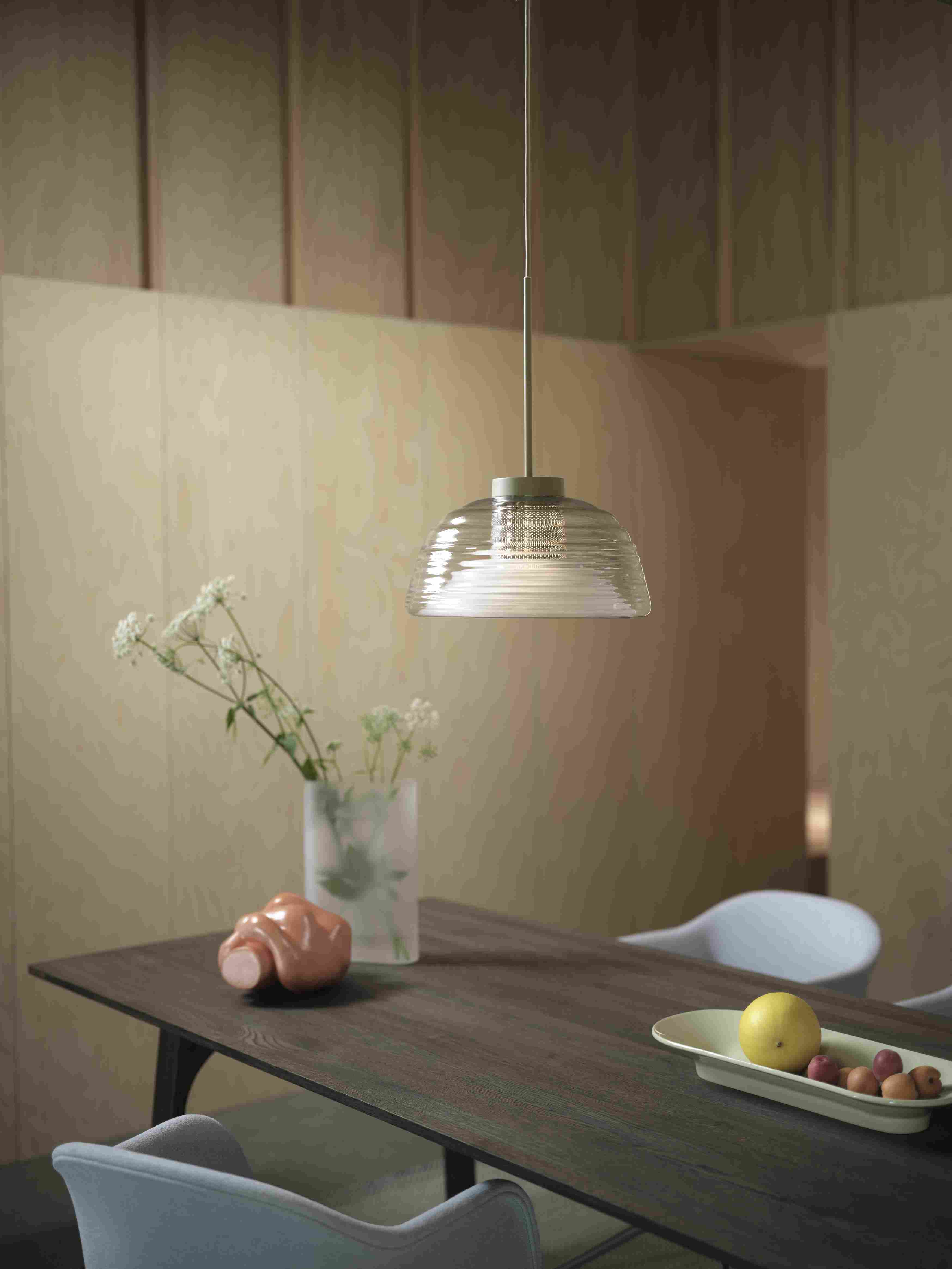 Muuto Two-Layer Pendelleuchte aus Glas über Esstisch mit Dekoration, modernes skandinavisches Design.