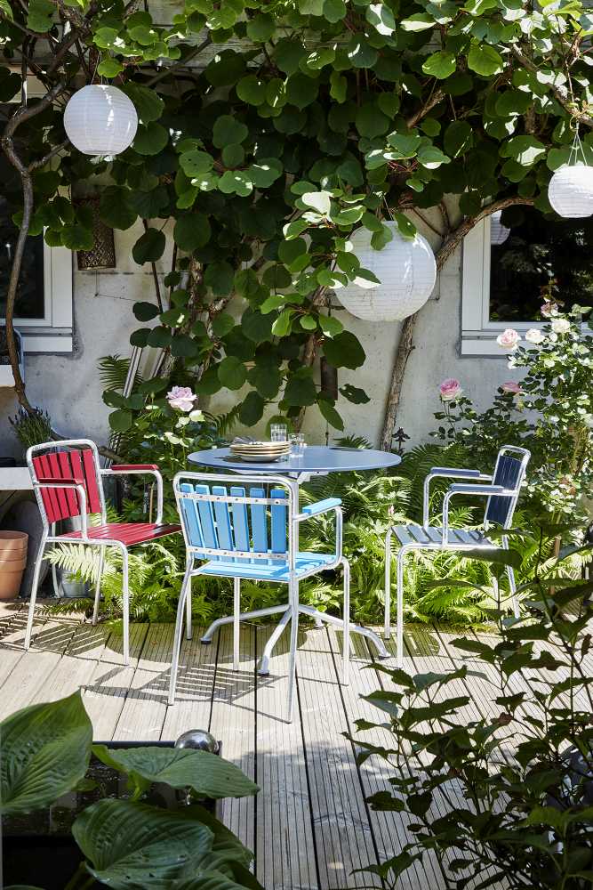 Haefeli Gartentisch Ø 60 cm graublau auf Holzterrasse mit Stühlen und üppiger Gartenbepflanzung. Outdoor Tisch.