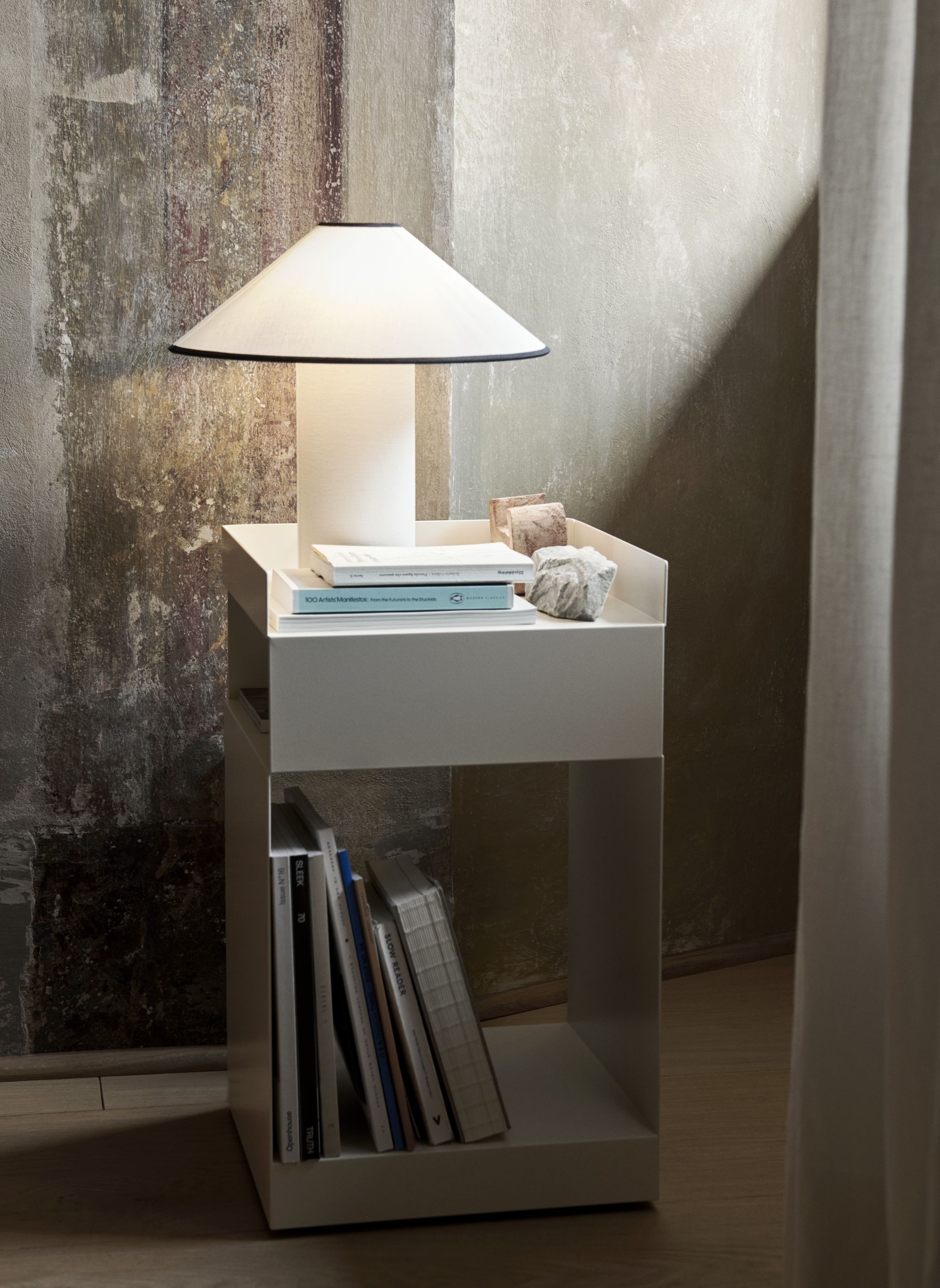 AndTradition Colette Tischleuchte ATD6 auf weißem Nachttisch mit Büchern und Dekoration. Moderne Tischlampe für Schlafzimmer.
