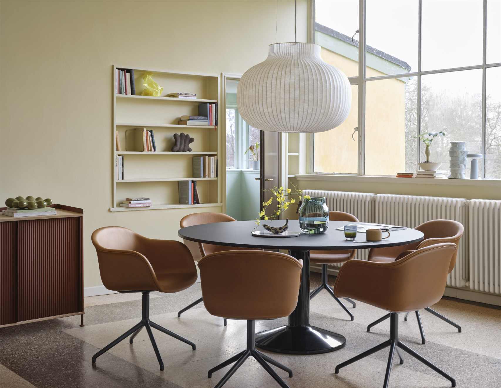 MIDST Table von Muuto: Runder Esstisch in Schwarz mit braunen Stühlen in einem Esszimmer.