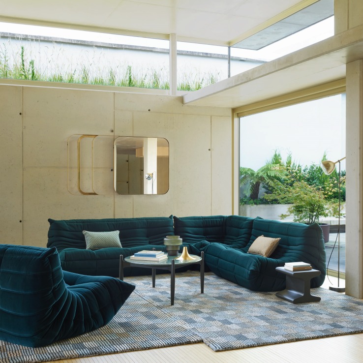 Dunkelgrüner Togo Sessel von Ligne Roset in modernem Wohnzimmer mit großem Fenster und Designermöbeln.