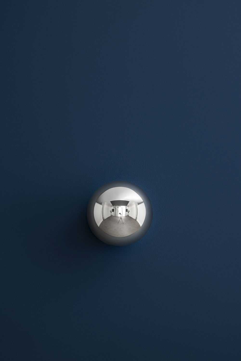 Sfera Wandleuchte von Catellani & Smith: Runde, silberne Designleuchte an blauer Wand. Reflektierendes Licht.