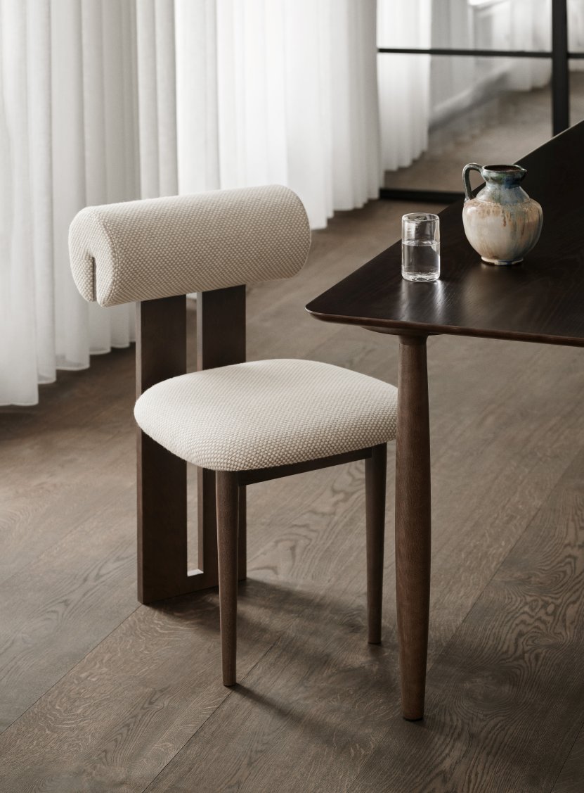 NORR11 Hippo Stuhl mit beigem Stoffbezug und dunklem Holzgestell am Esstisch.