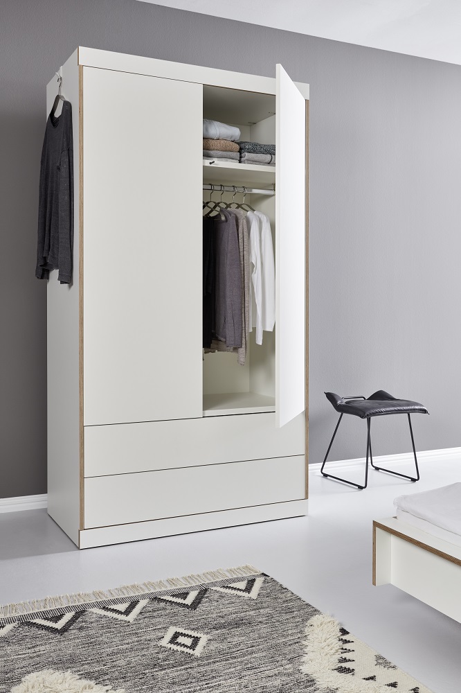 Weißer Kleiderschrank mit Schubladen und offener Tür, Innenraum mit Kleidung und Ablagefächern. Moderner Schrank für Schlafzimmer.