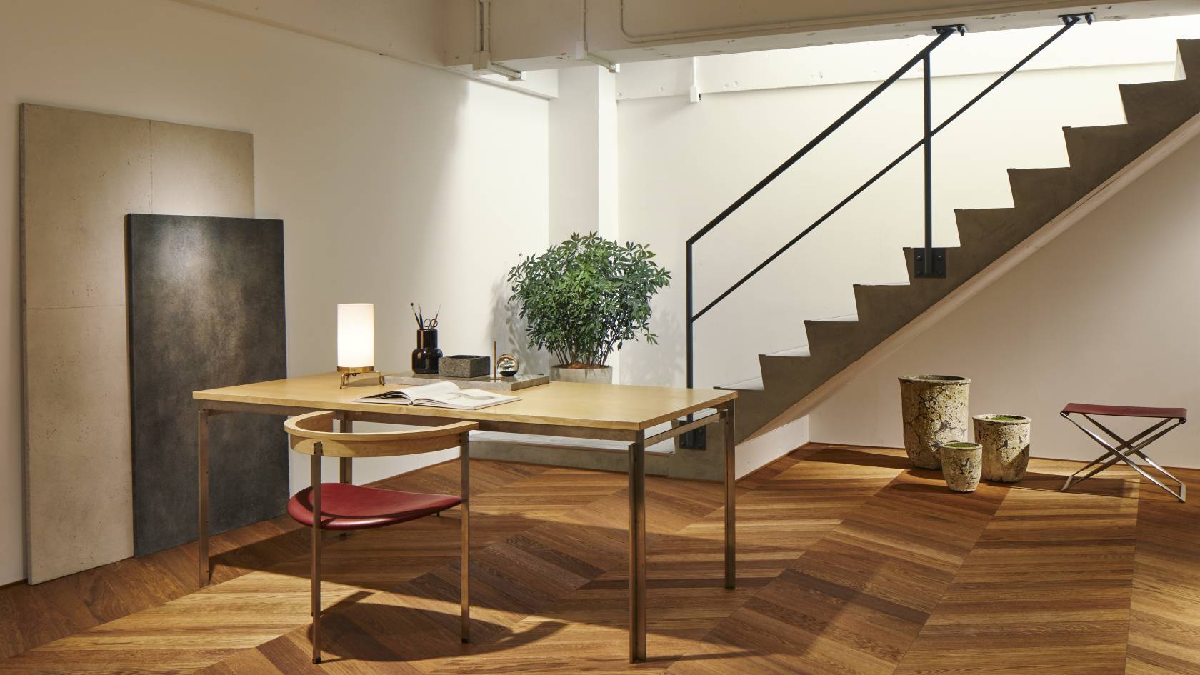 PK91 Falthocker von Fritz Hansen im Interieur mit Schreibtisch, Stuhl und Treppe.