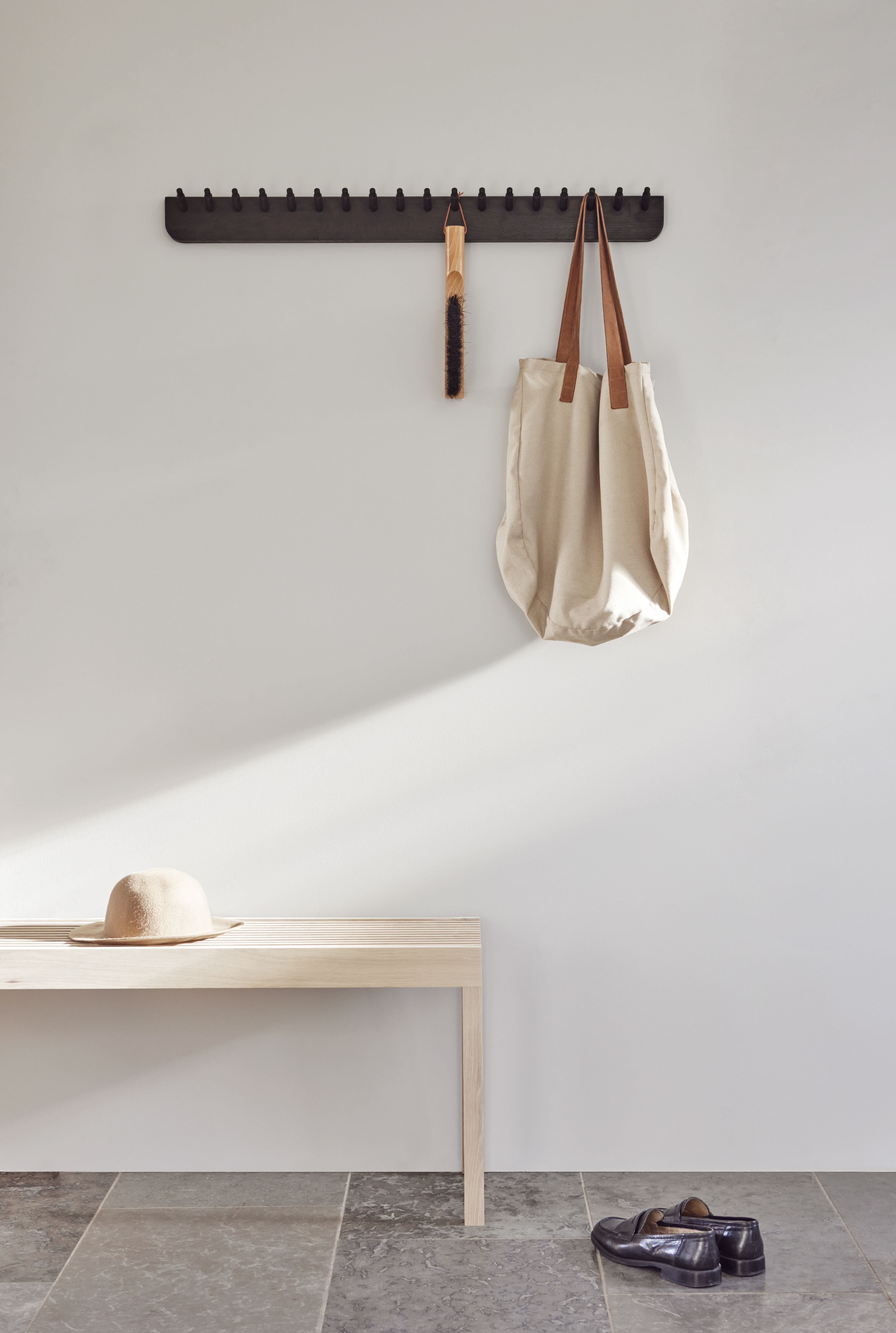 Echo Garderobenleiste von Form & Refine aus Eiche mit Tasche, Bürste und Hut im Flur.