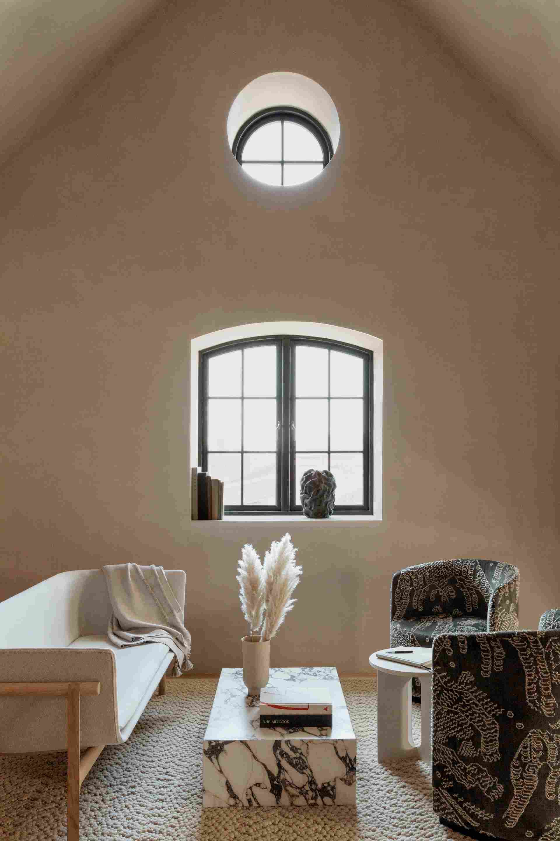 Wohnzimmer Interieur mit Audo Copenhagen Plinth Marmor Couchtisch, Sofa, Sesseln und Dekoration in natürlichem Licht.