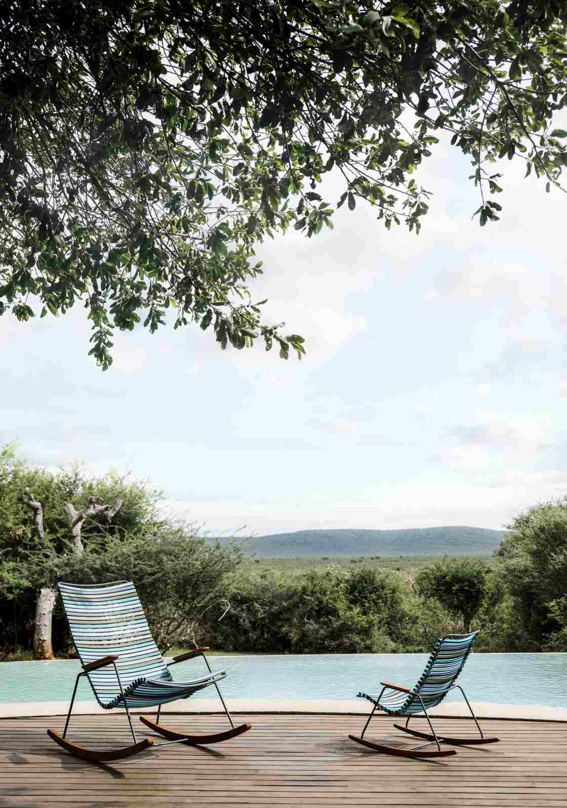 Zwei Click Schaukelstühle von Houe im Freien am Pool mit schöner Aussicht.
