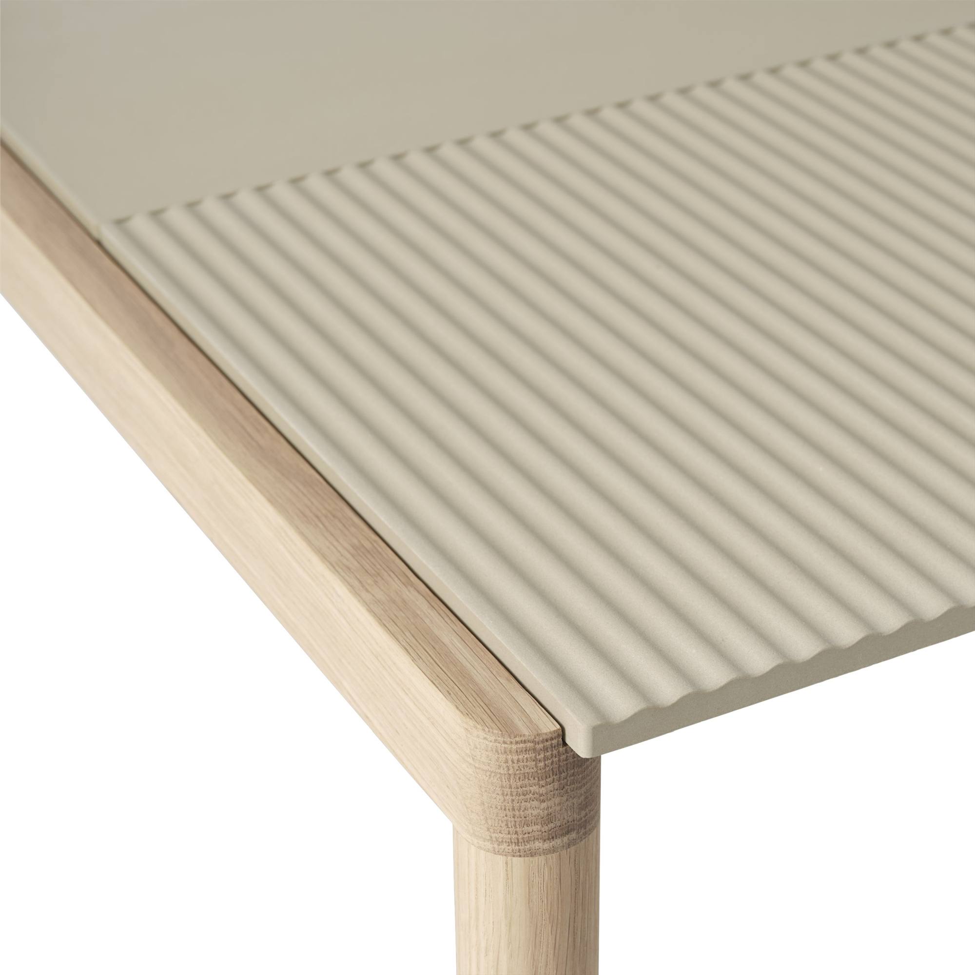 Detailaufnahme des Muuto Couple Coffee Table: Beige Tischplatte mit Rillenmuster und hellem Holzgestell.