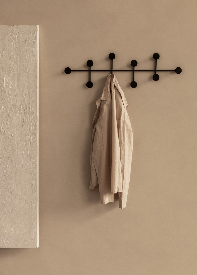 Schwarzer Afteroom Garderobenhaken von Audo mit hängender Jacke an beiger Wand. Design Garderobe.
