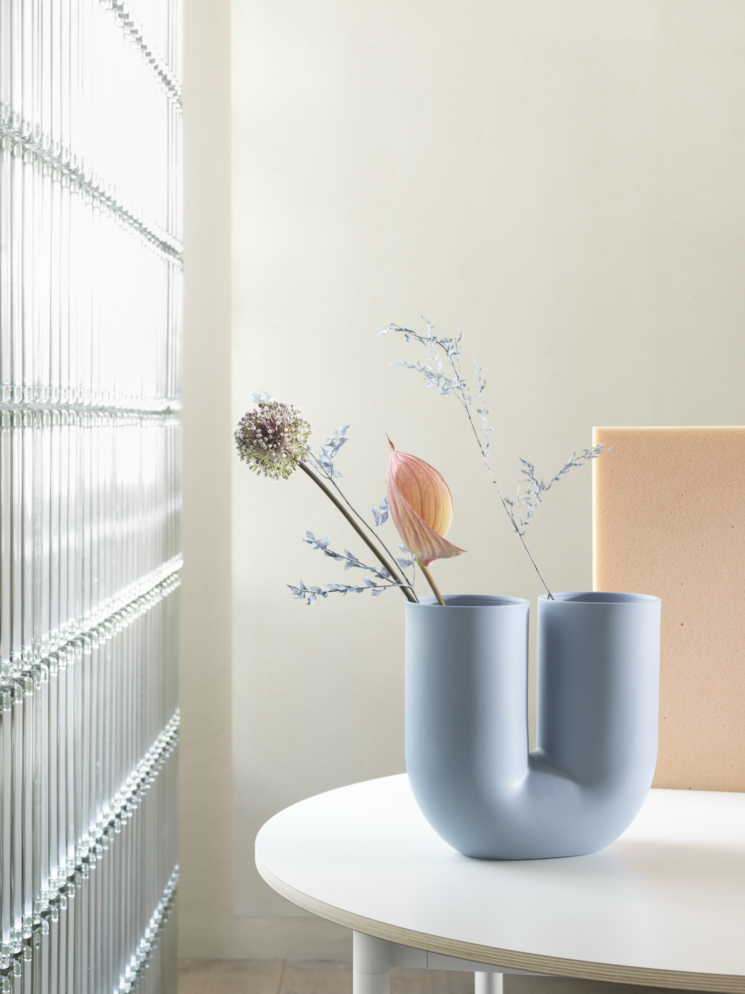 Kink Vase SAND von Muuto mit Blumen auf einem weißen Tisch. Moderne Dekoration.