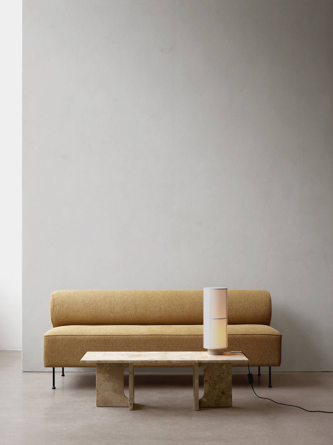 Audo Hashira Tischleuchte auf Marmortisch neben gelbem Sofa, moderne Innenraumbeleuchtung.