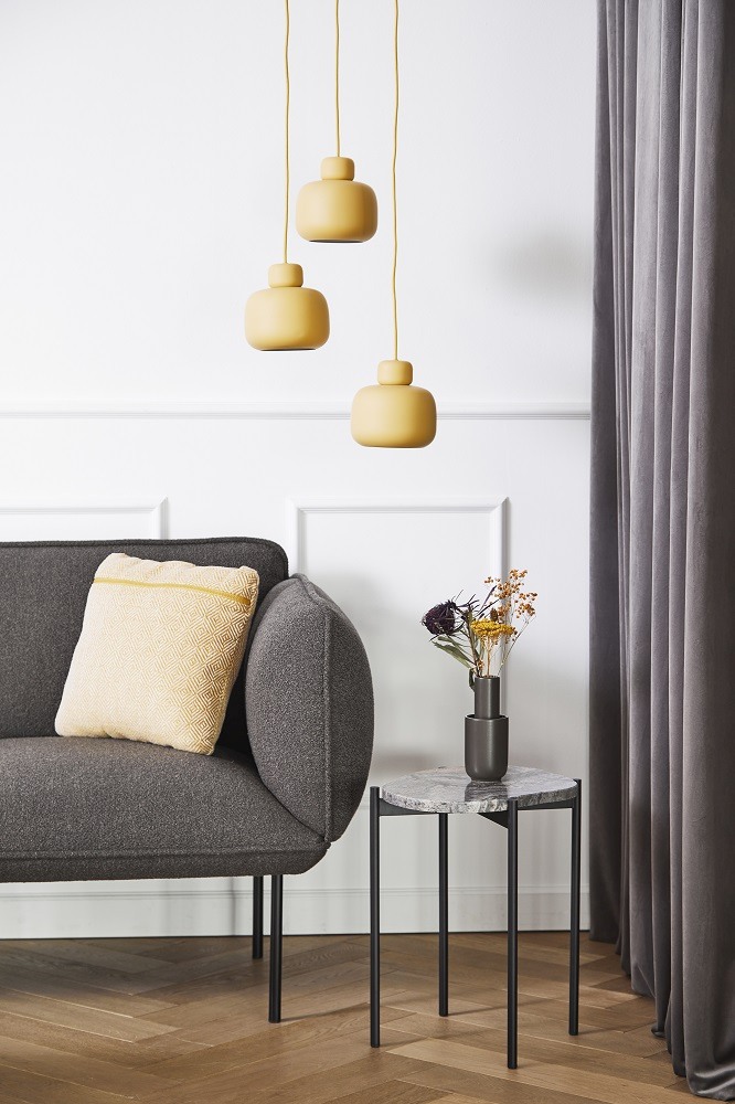 La Terra Beistelltisch von Woud neben einem Sofa mit Lampe und Dekoration.