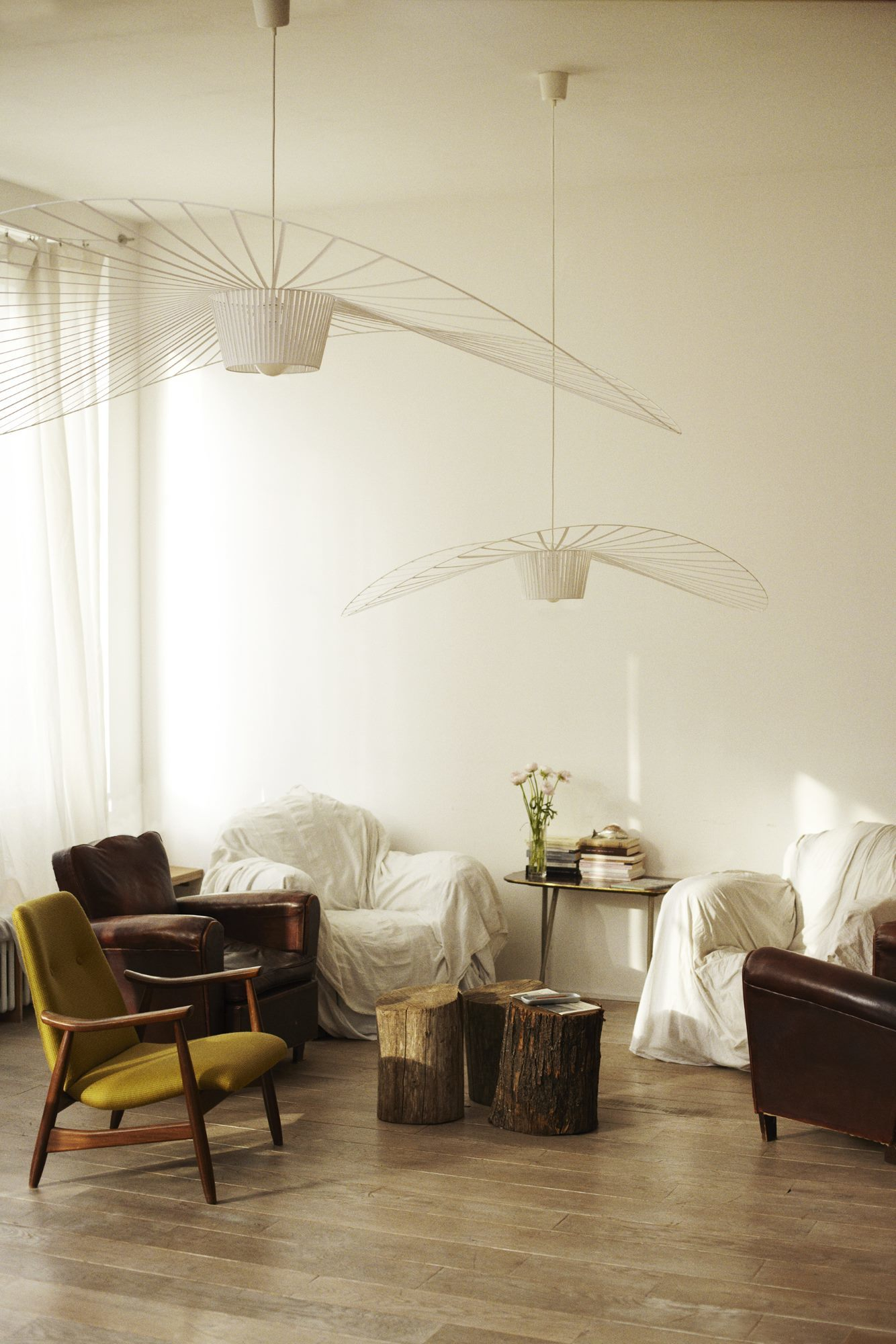 Helle Wohnzimmer-Szene mit zwei großen, weißen Vertigo Pendelleuchten von Petite Friture als stilvolle Beleuchtung.