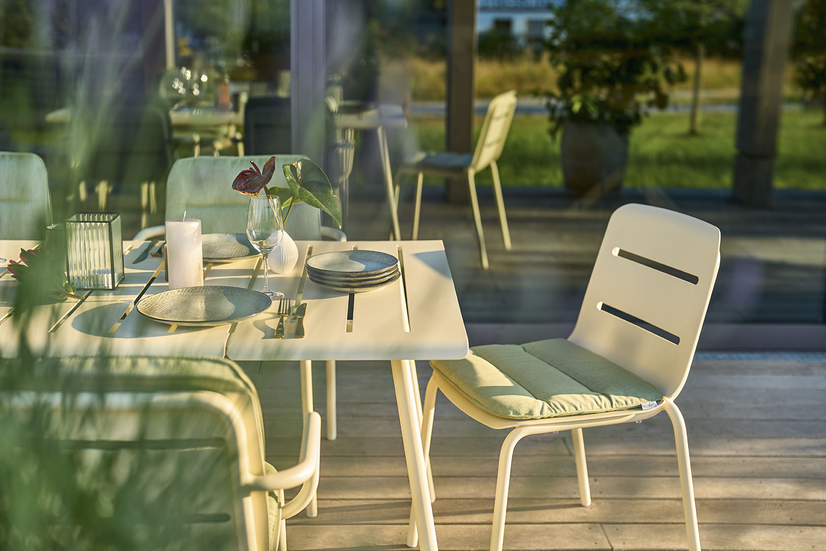 Weishäupl Vapio Tisch Outdoor mit Stühlen und Tischdeko auf einer Terrasse, Fokus auf Gartentisch und Stuhl.