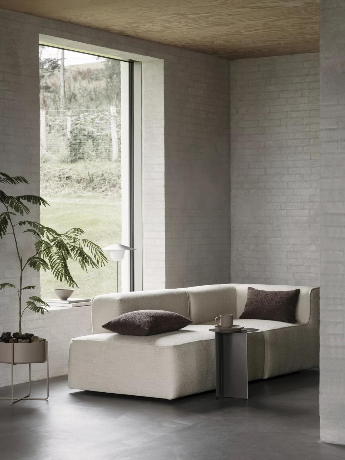 Oru Beistelltisch von Blomus in Burned Metal neben einem Sofa in einem hellen Wohnraum.