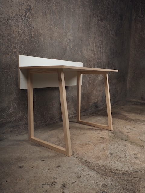 Tojo Kids Werk Schreibtisch aus Holz mit weißer Platte vor einer grauen Wand.