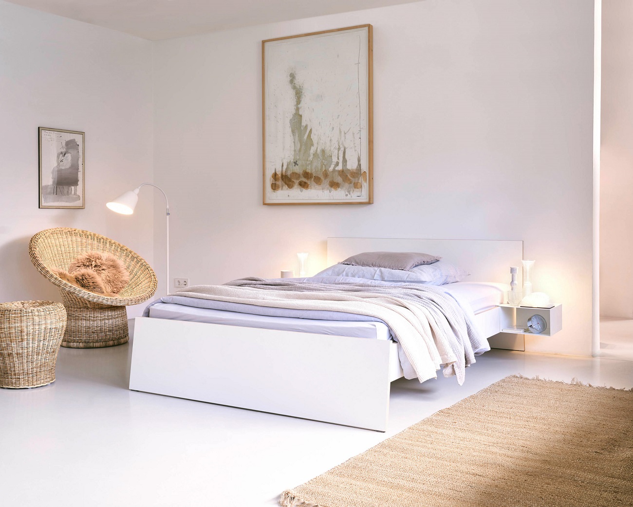 Weißes Bett mit Nachttisch zum Einhängen von Richard Lampert, minimalistisches Schlafzimmer Design mit Teppich und Korbsessel.