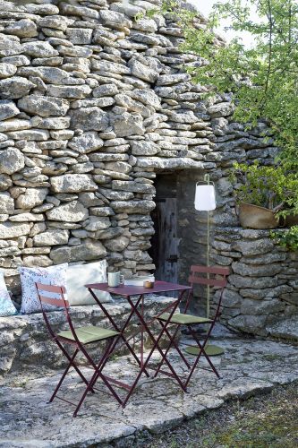 Fermob Bistro Tisch und Stühle Outdoor vor Steinwand. Gartenmöbel für Terrasse und Balkon.