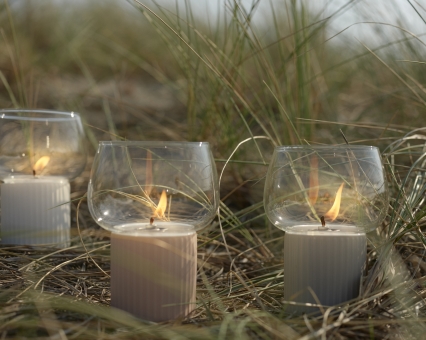 Drei Windlichter mit Glasaufsatz und brennenden Kerzen im Freien, dekorative Outdoor-Beleuchtung.