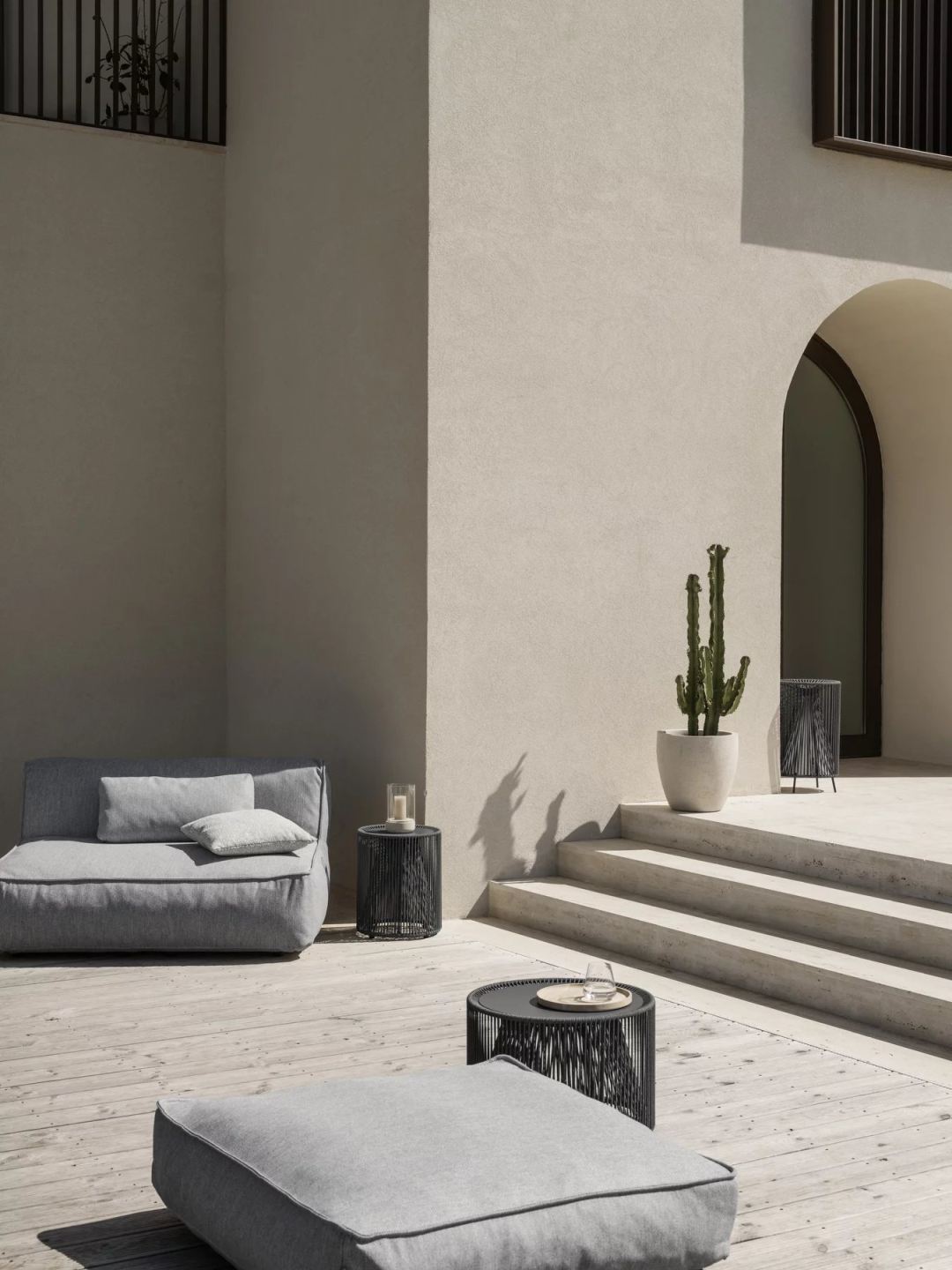 Graues Outdoor-Sofa mit Grow Kissen von Blomus Coal und Beistelltischen auf einer Terrasse.