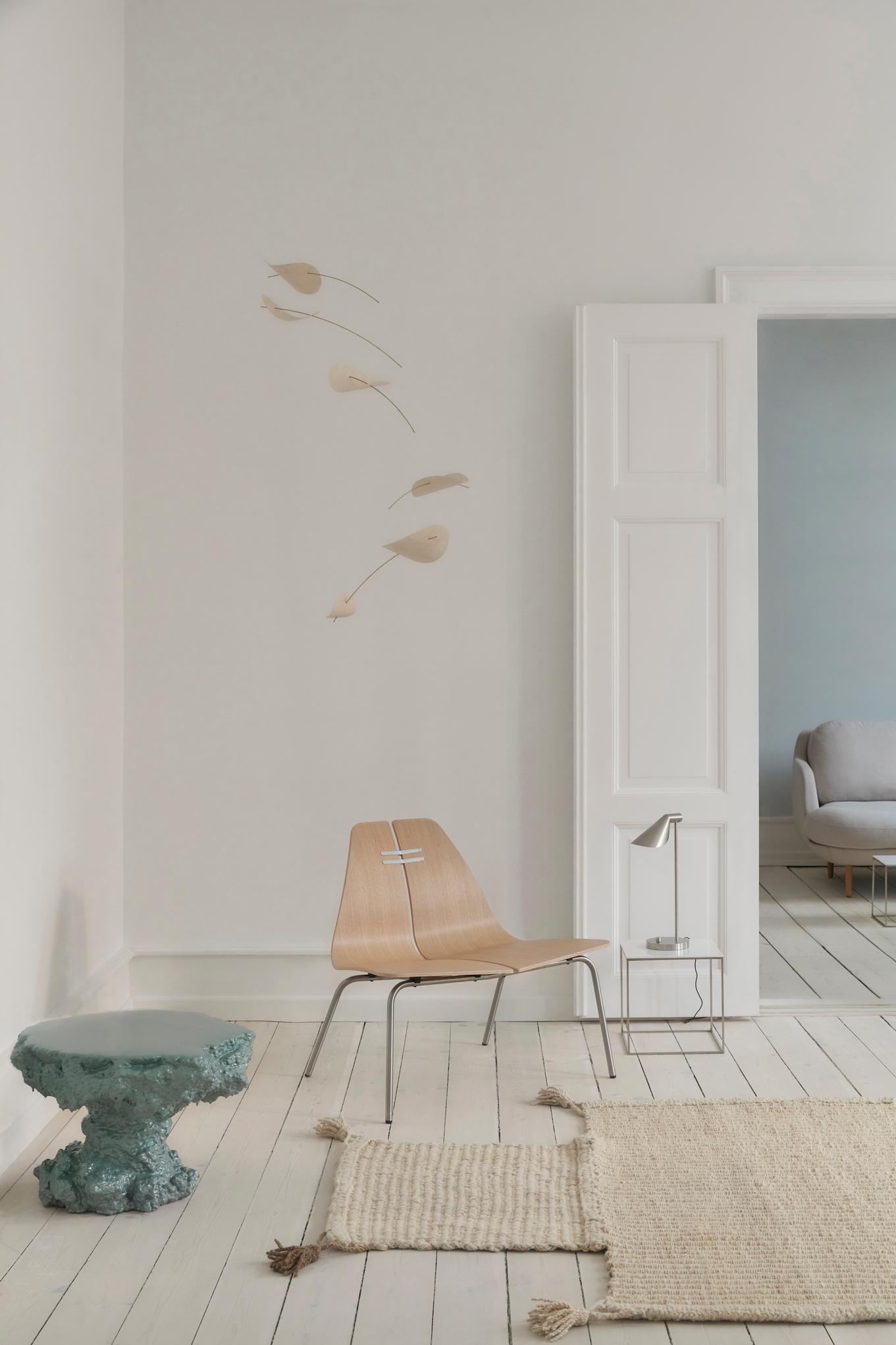 Heller Raum mit PK23 Loungesessel von Fritz Hansen, Beistelltisch und Teppich auf weißem Holzboden.
