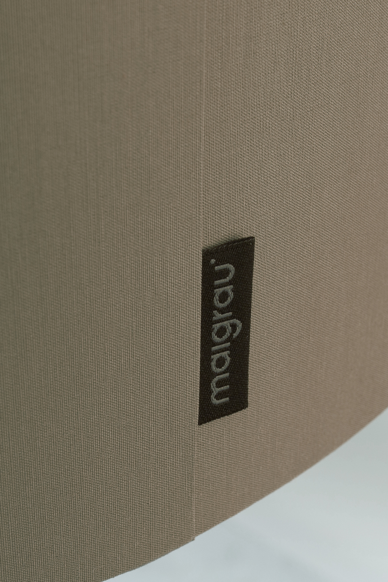 Detailaufnahme der beigen Luca Anlehnleuchte von Maigrau, Fokus auf Stoffstruktur und Markenlabel.