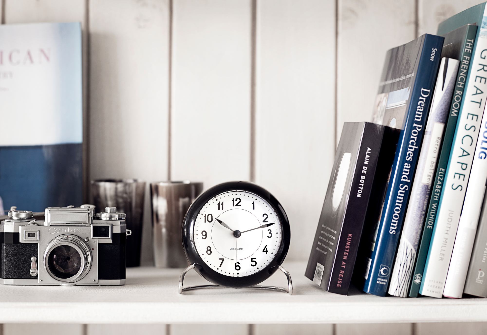 Arne Jacobsen Tischuhr Station auf Regal mit Kamera und Büchern. Zeitmesser für Wohnzimmer.