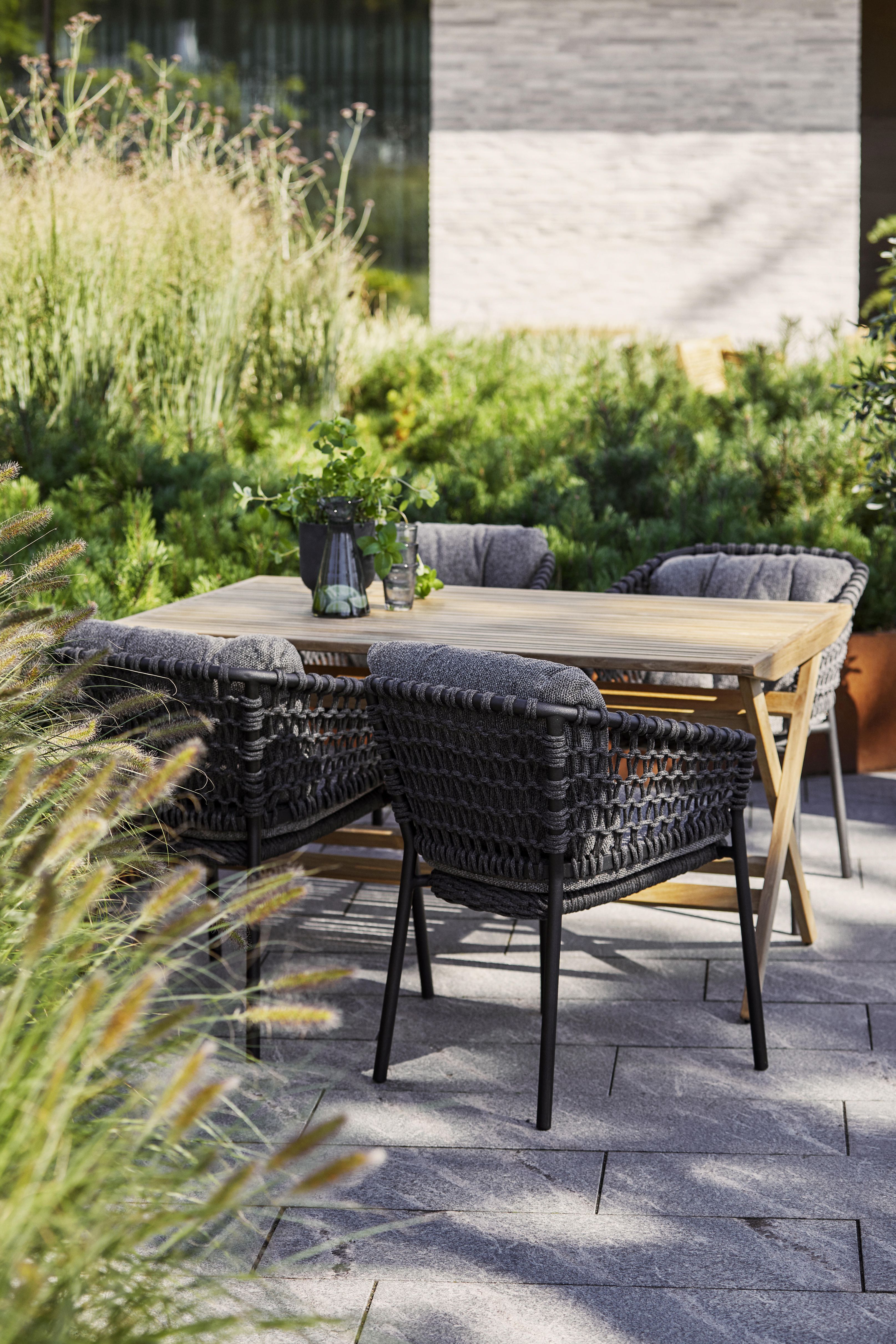 Nahaufnahme von Cane-Line Ocean Lounge Stühlen und Holztisch im Garten, Outdoor Möbel.