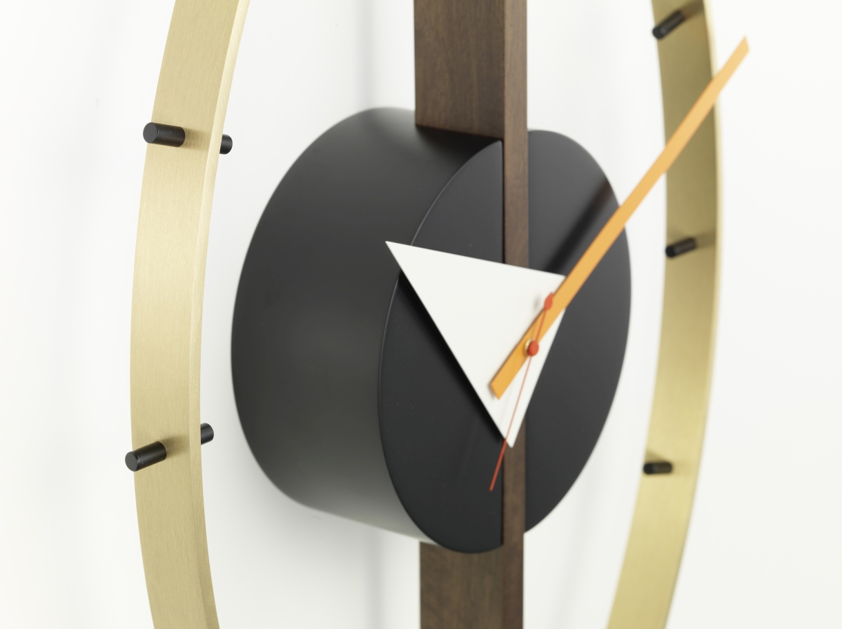 Detailaufnahme der Vitra Eye Clock Wanduhr mit goldenem Rahmen, schwarzem Zifferblatt und farbigen Zeigern.
