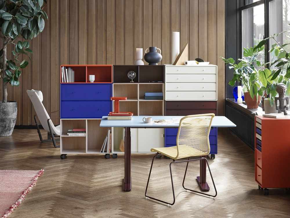 HiLow 2 Montana höhenverstellbarer Schreibtisch in einem modernen Büro mit Regalen und Stuhl.