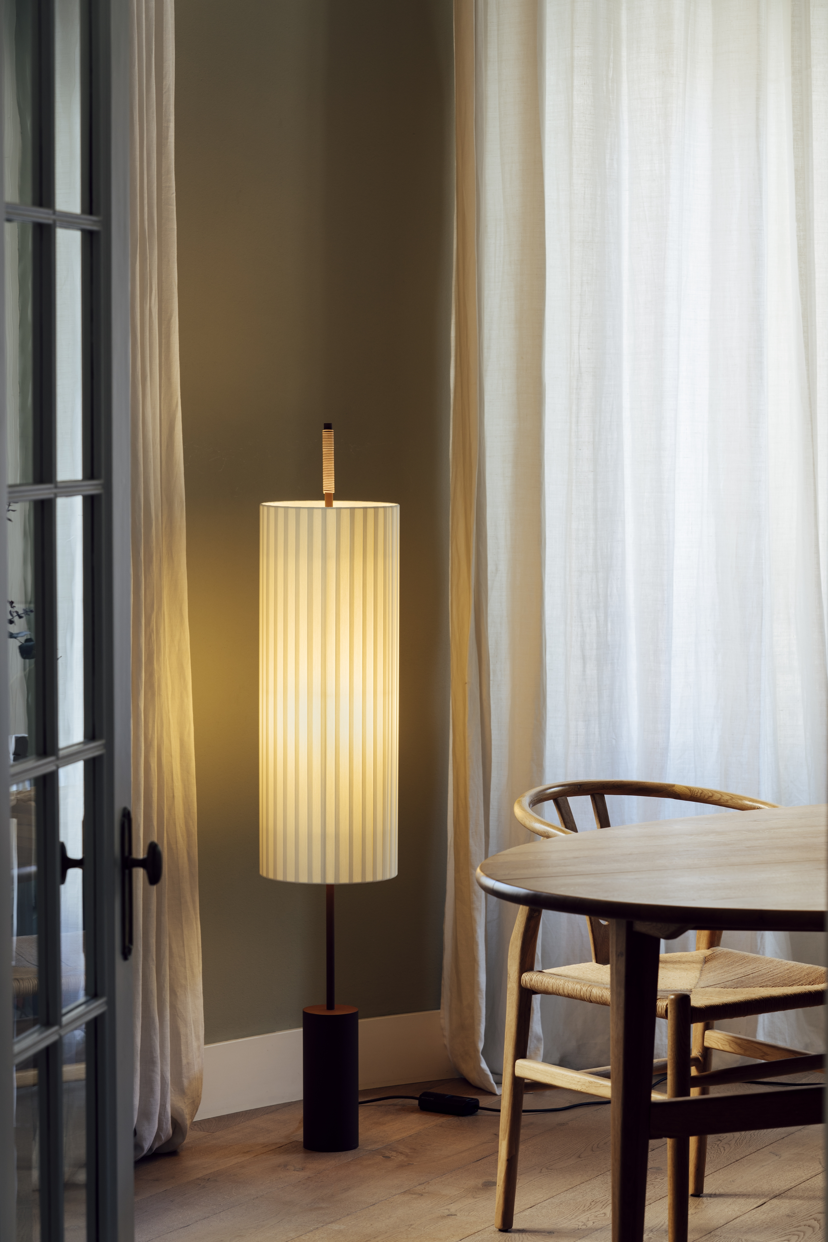 Dorica Stehleuchte von Santa & Cole mit gestreiftem Lampenschirm und warmem Licht im Wohnraum.